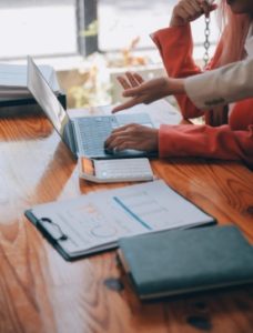 Client consulting with CPA across desk, organized tax documents, calculator, laptop, friendly professional interaction, warm lighting, high detail